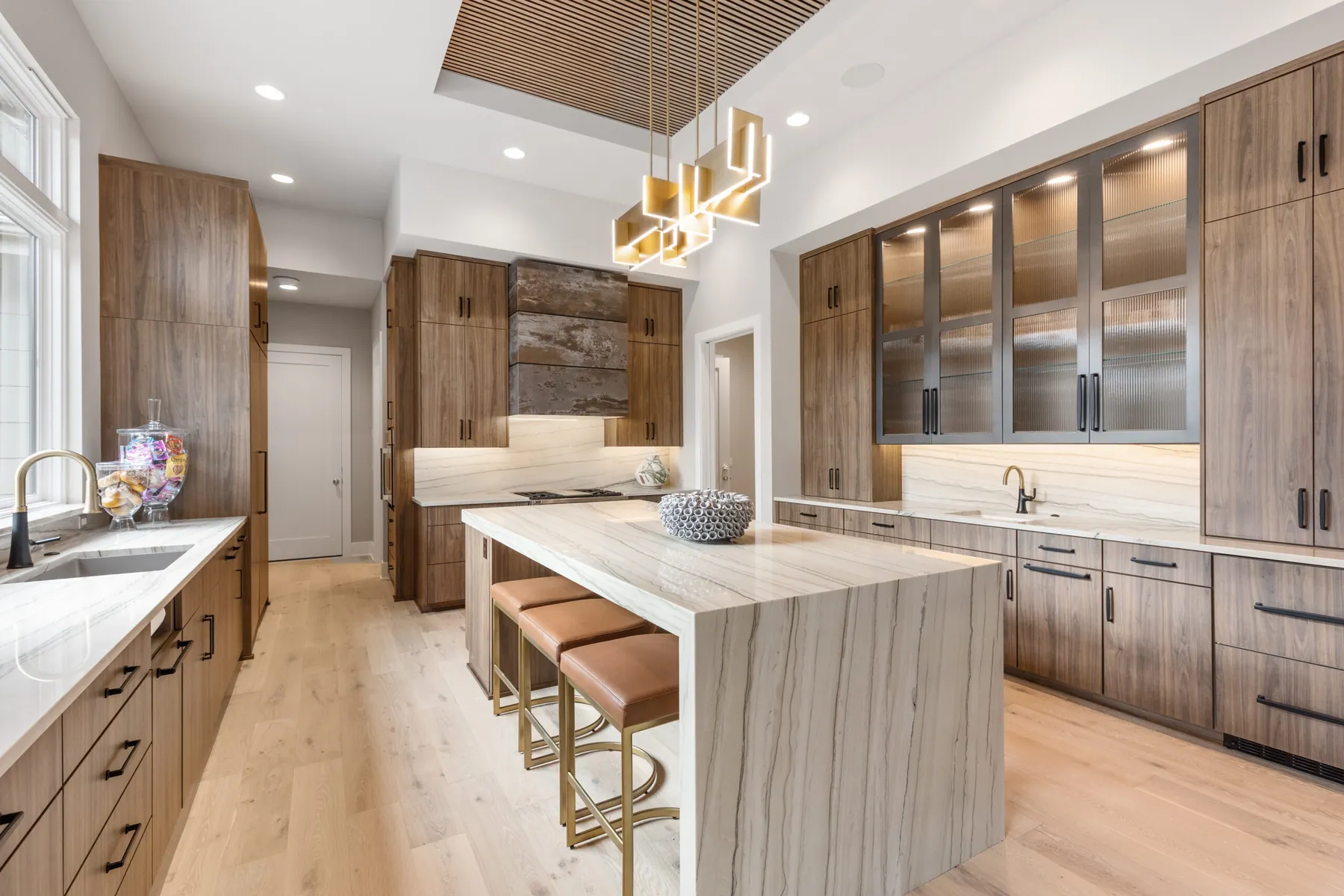Walnut kitchen with quartzite island and reeded-glass uppers
